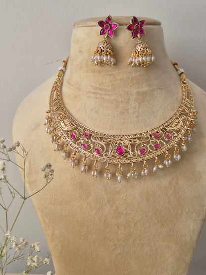 Komal Necklace Set: Gold-polished temple choker with pink stone accents, small dangling seed pearls, and coordinating festive jhumkas from the Naitri collection by naitri.in