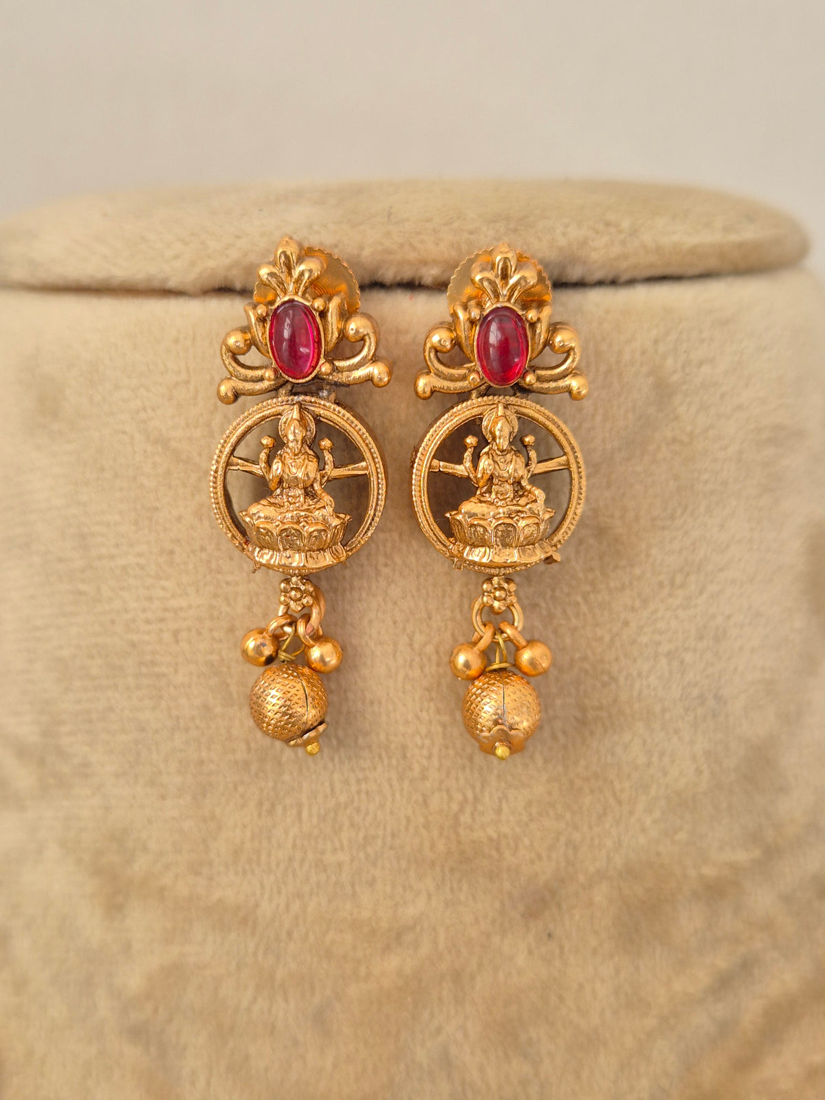 Handcrafted gold-toned drop earrings featuring intricate goddess with stone embellishments by naitri.in