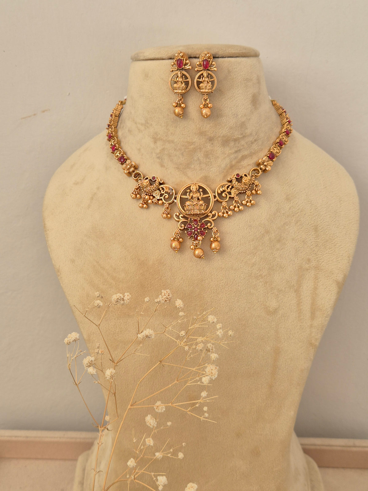 Handcrafted gold-toned choker necklace set featuring intricate stone embellishments, matching drop earrings by naitri.in