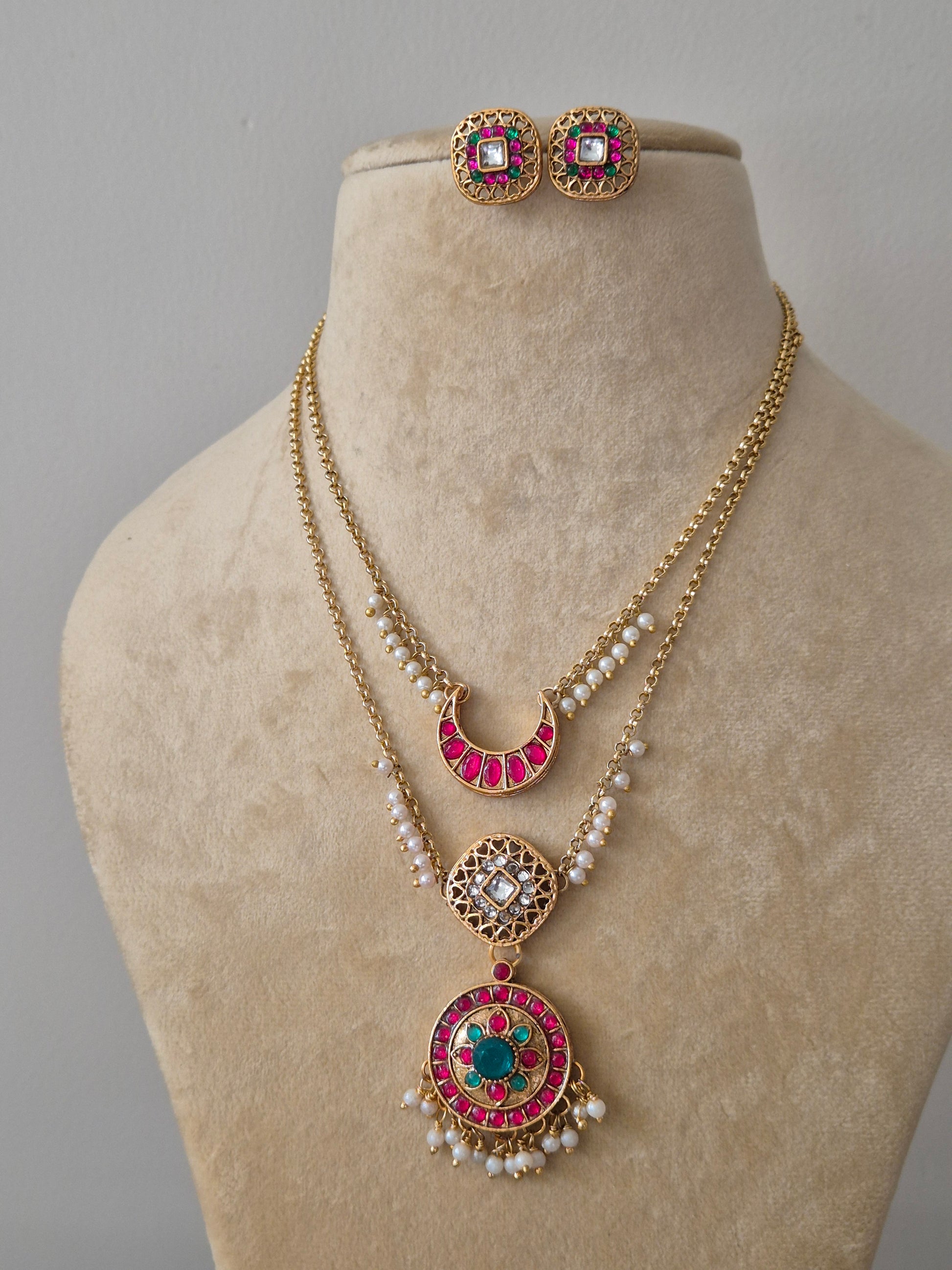 Handcrafted ethnic jewelry set including a multi-layered gold chain necklace with intricate stone-studded pendants and matching square-shaped pink and green earrings by naitri.in