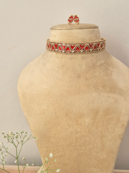An elegant gold-plated choker necklace featuring a repeating pattern of red enamel heart-shaped motifs by naitri.in