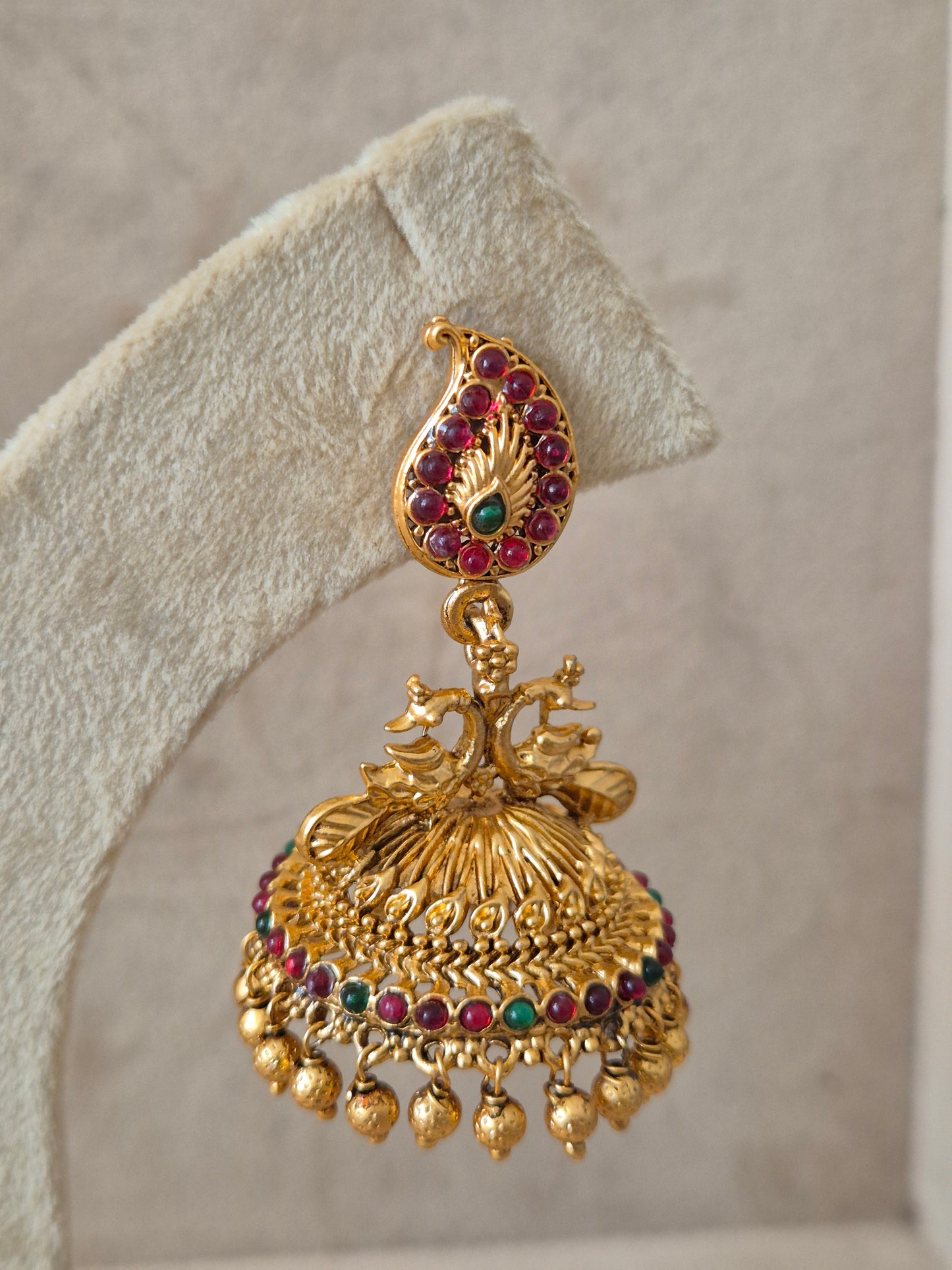Handcrafted  earrings in brass alloy with a polished golden finish and vibrant red and green stone embellishments by naitri.in