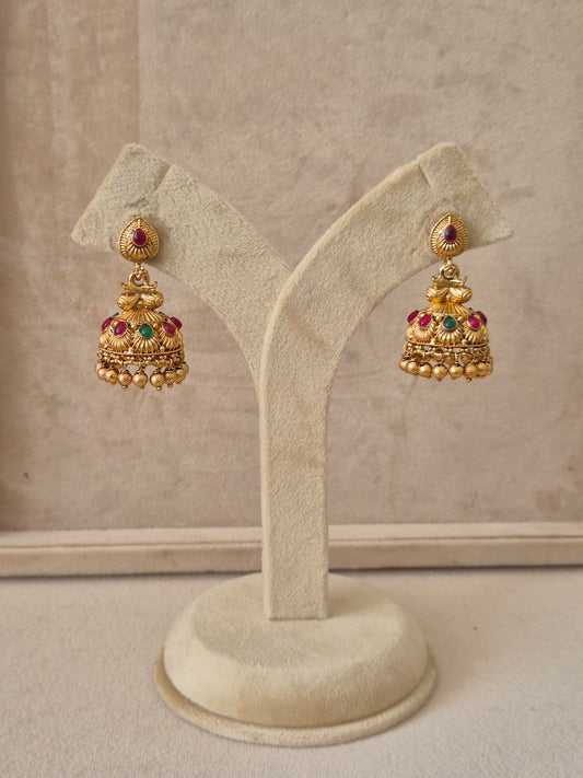 Traditional gold-toned Jhumka earrings featuring intricate floral studs with red and green gemstone accents and gold bead drops by naitri.in