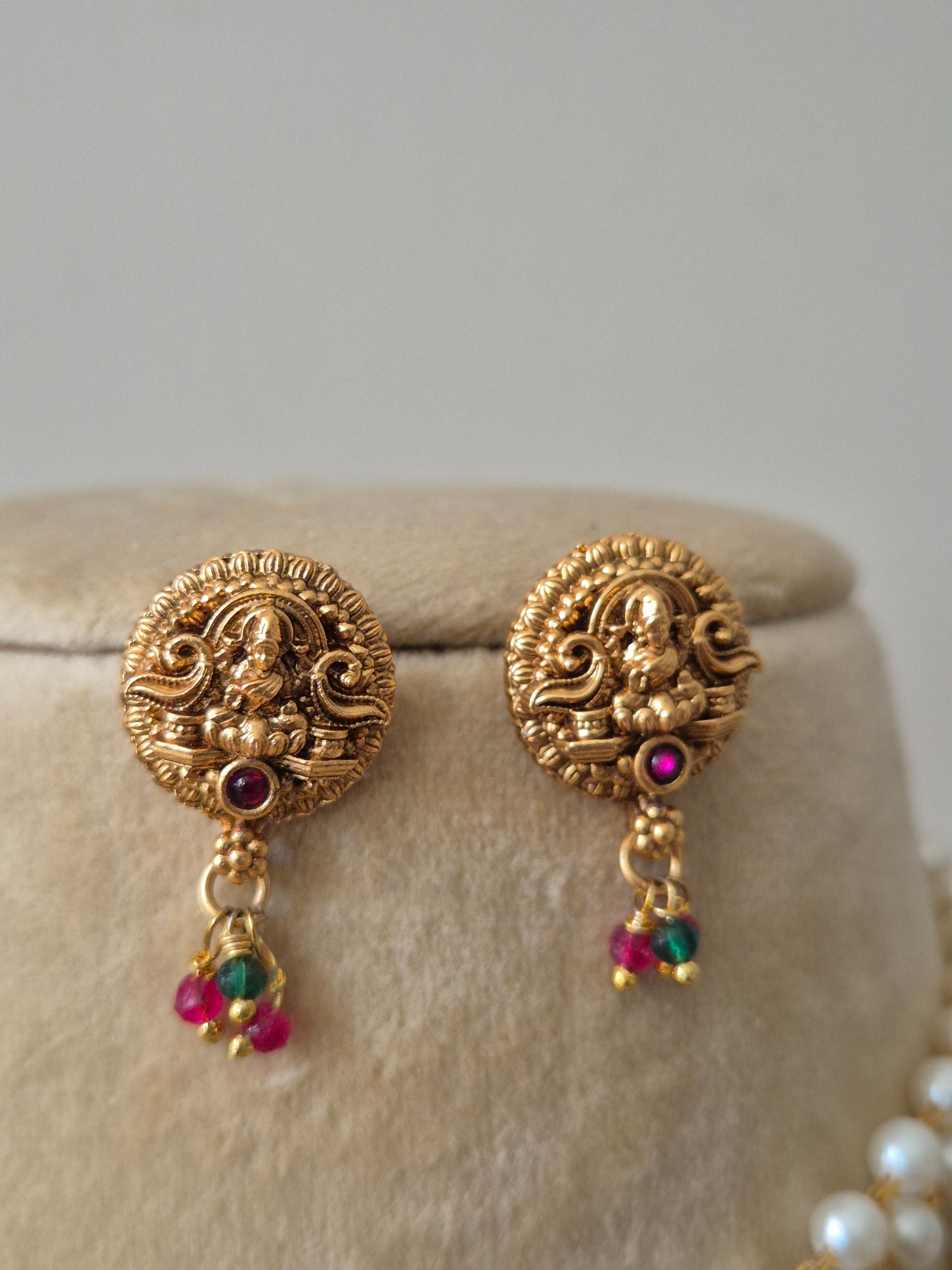 Gold earrings with intricate designs and colorful beads by naitri.in