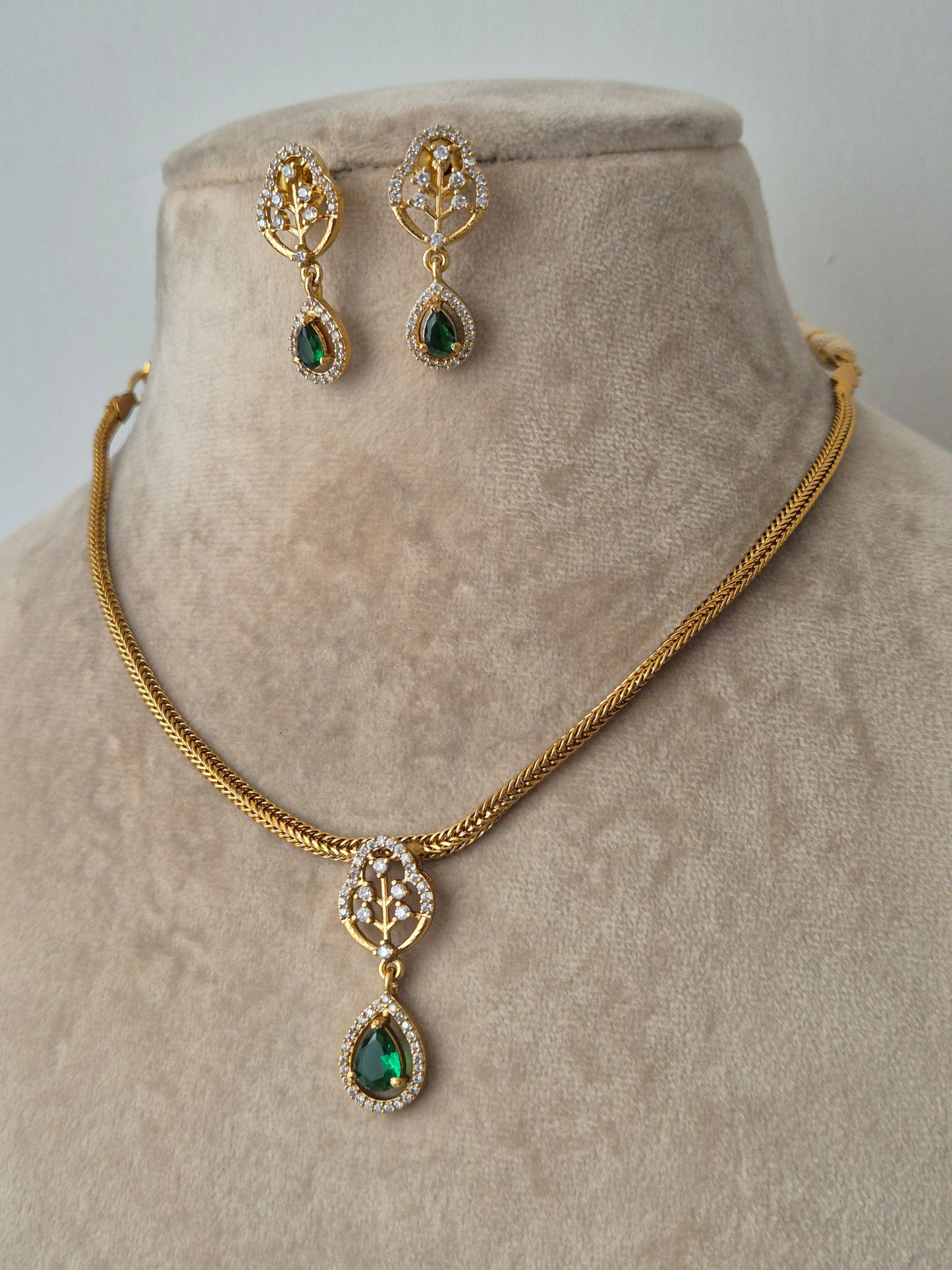 Gold jewelry set with green gemstones handcrafted drop shaped piece attached with leaf shaped pendant 