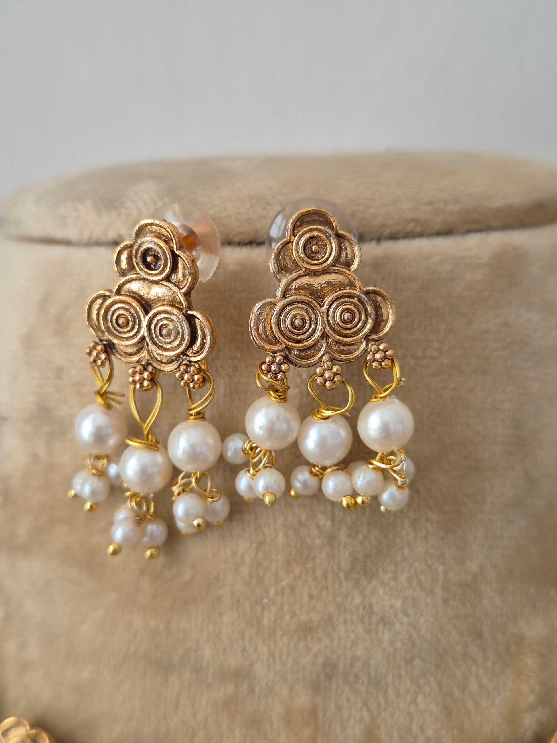 Modern Indian traditional imitation earrings, golden brass alloy with delicate floral detailing and cascading white pearl tassels by naitri.in