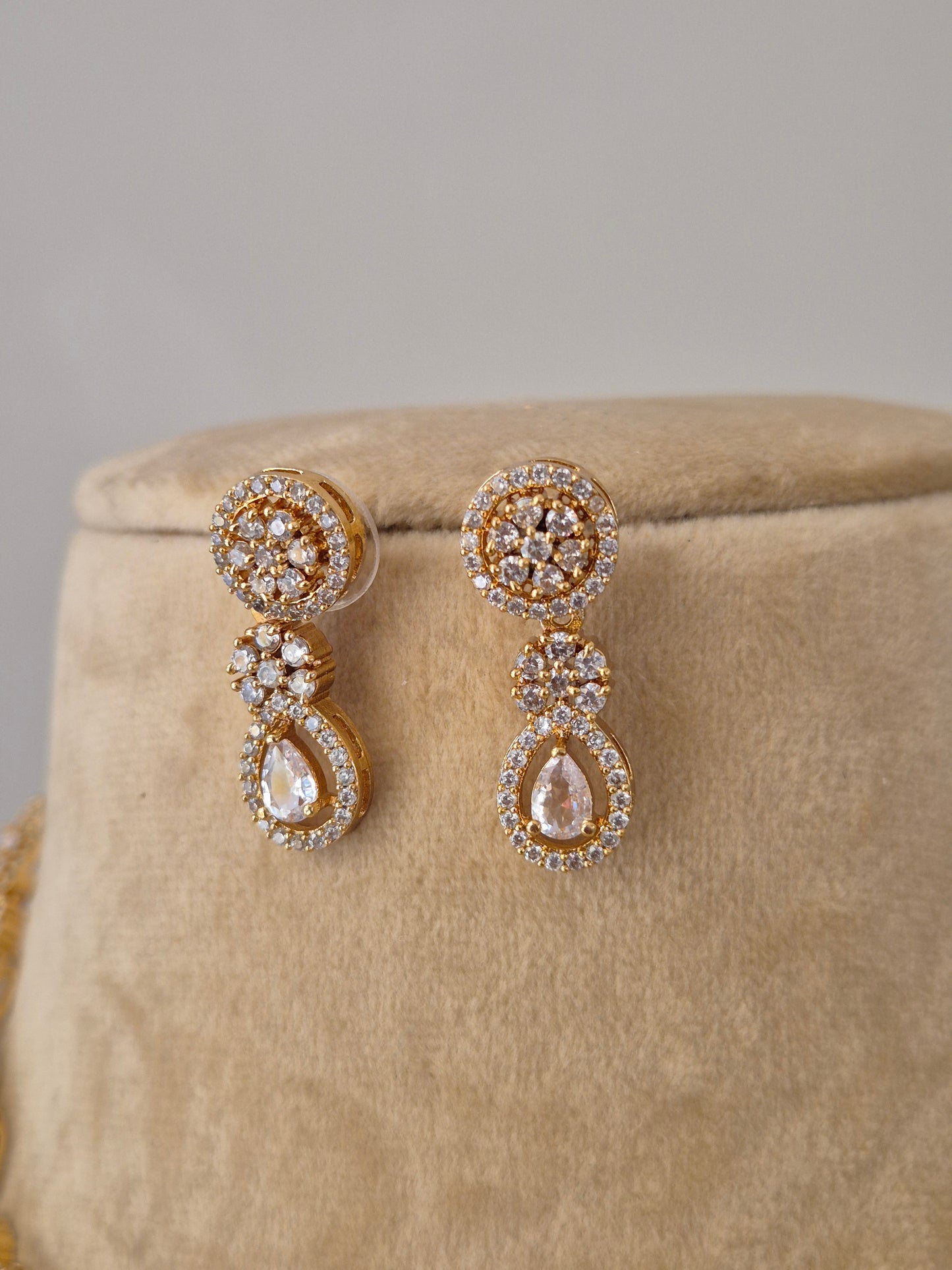 Pair of gold earrings with clear stones  flower and tear drop designed earring by naitri.in