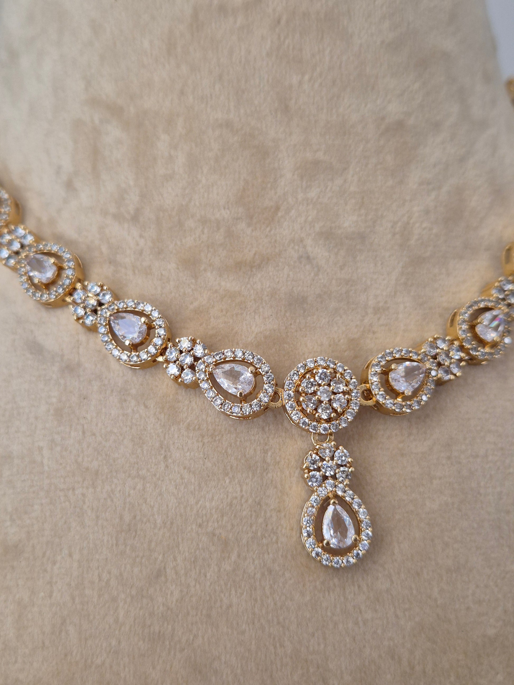  gold necklace with diamond-like stones Close-up of the Lisha Necklace Set from Naitri, featuring a delicate floral stone-studded design in brass alloy, by naitri.in