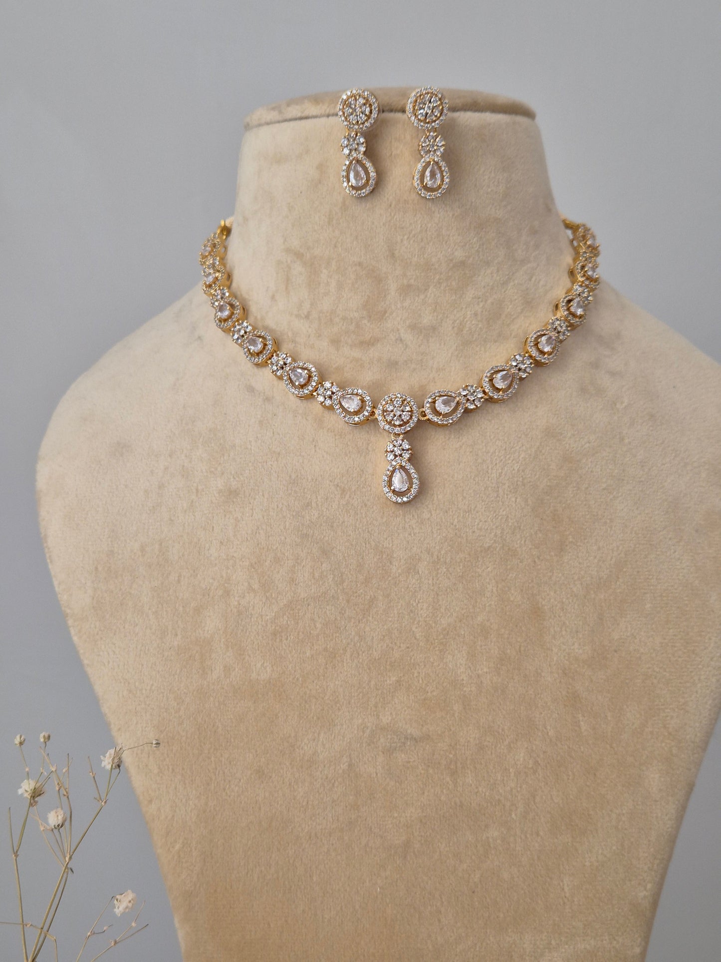 Gold-plated necklace set with intricate stone embellishments and matching stud earrings by naitri.in