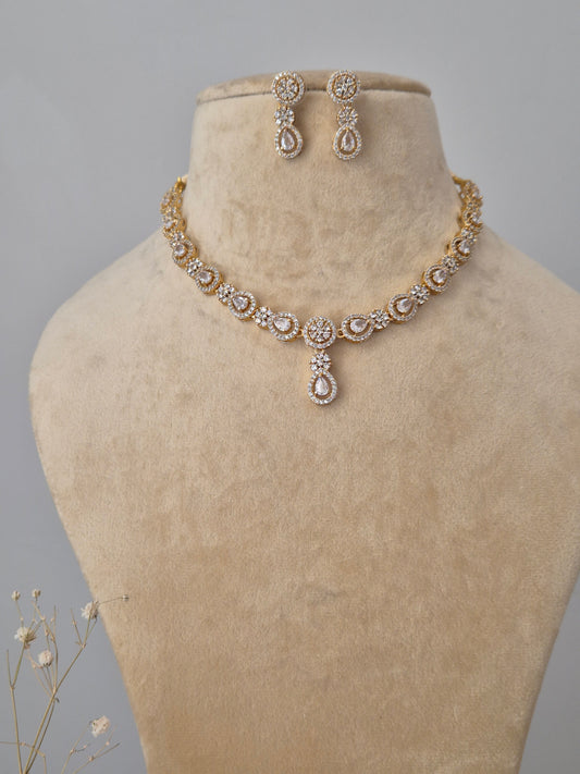 Gold-plated necklace set with intricate stone embellishments and matching stud earrings by naitri.in