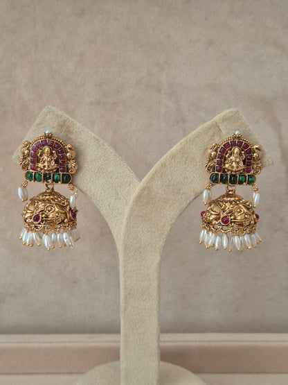 Ornate gold earrings with gemstones Traditional gold-toned temple design Jhumka earrings with red and green stones and tiny white pearl drops by naitri.in