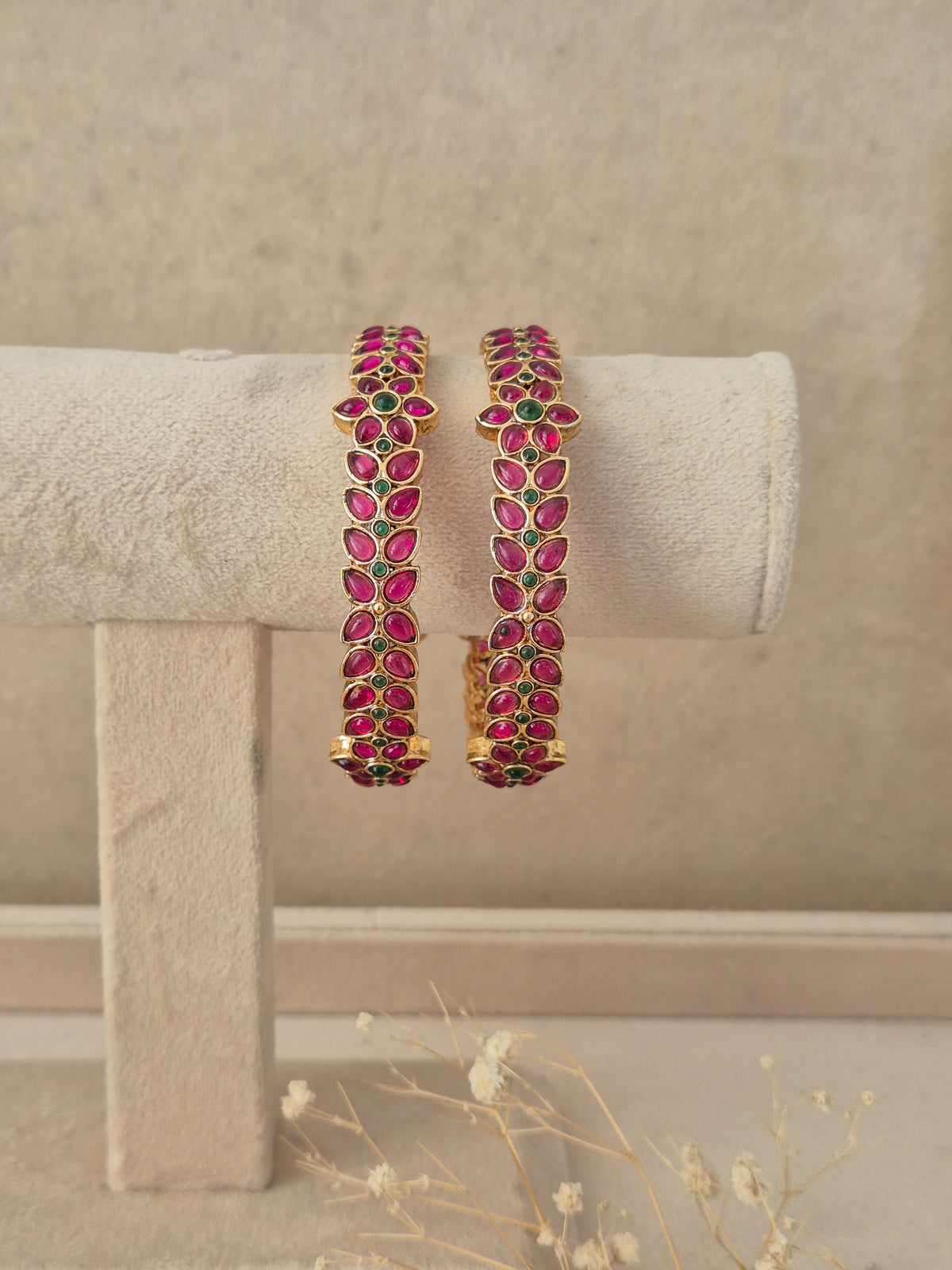 Set of 2 gold-plated bangles studded with marquise-cut pink and emerald green stones in a leaf motif, by naitri.in