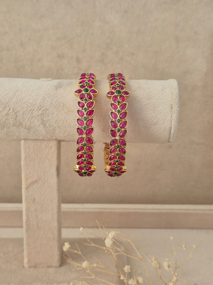 Set of 2 gold-plated bangles studded with marquise-cut pink and emerald green stones in a leaf motif, by naitri.in