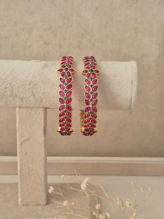 Set of 2 gold-plated bangles studded with marquise-cut pink and emerald green stones in a leaf motif, by naitri.in