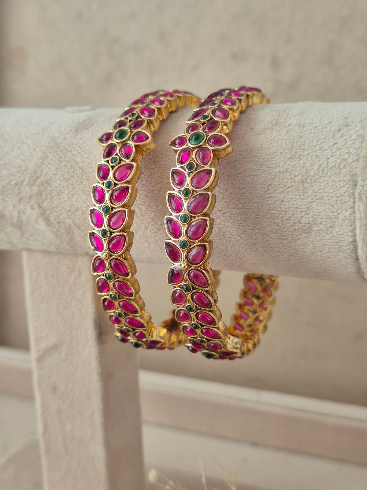 Festive Indian gold-plated bangles decorated with vibrant pink and green stone embellishments, perfect for weddings and special occasions by naitri.in