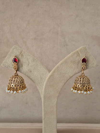 Traditional gold-plated Jhumka earrings with a red gemstone stud and tiny white pearl drops by naitri.in