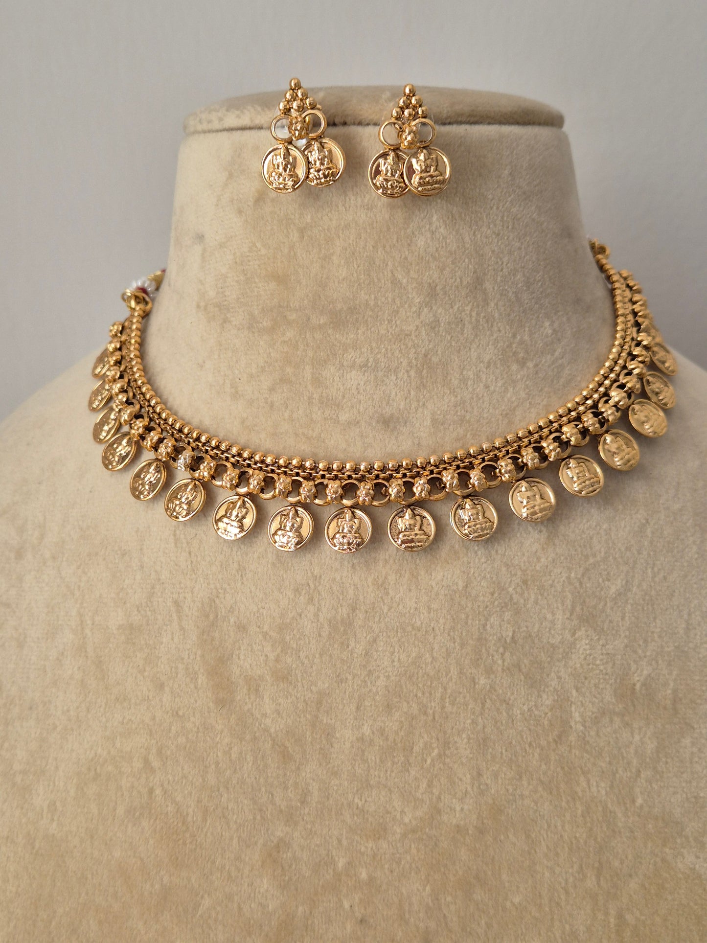 Malini Necklace Set: Gold-plated brass choker with a dangling temple coin fringe and coordinating festive stud earrings by naitri.in