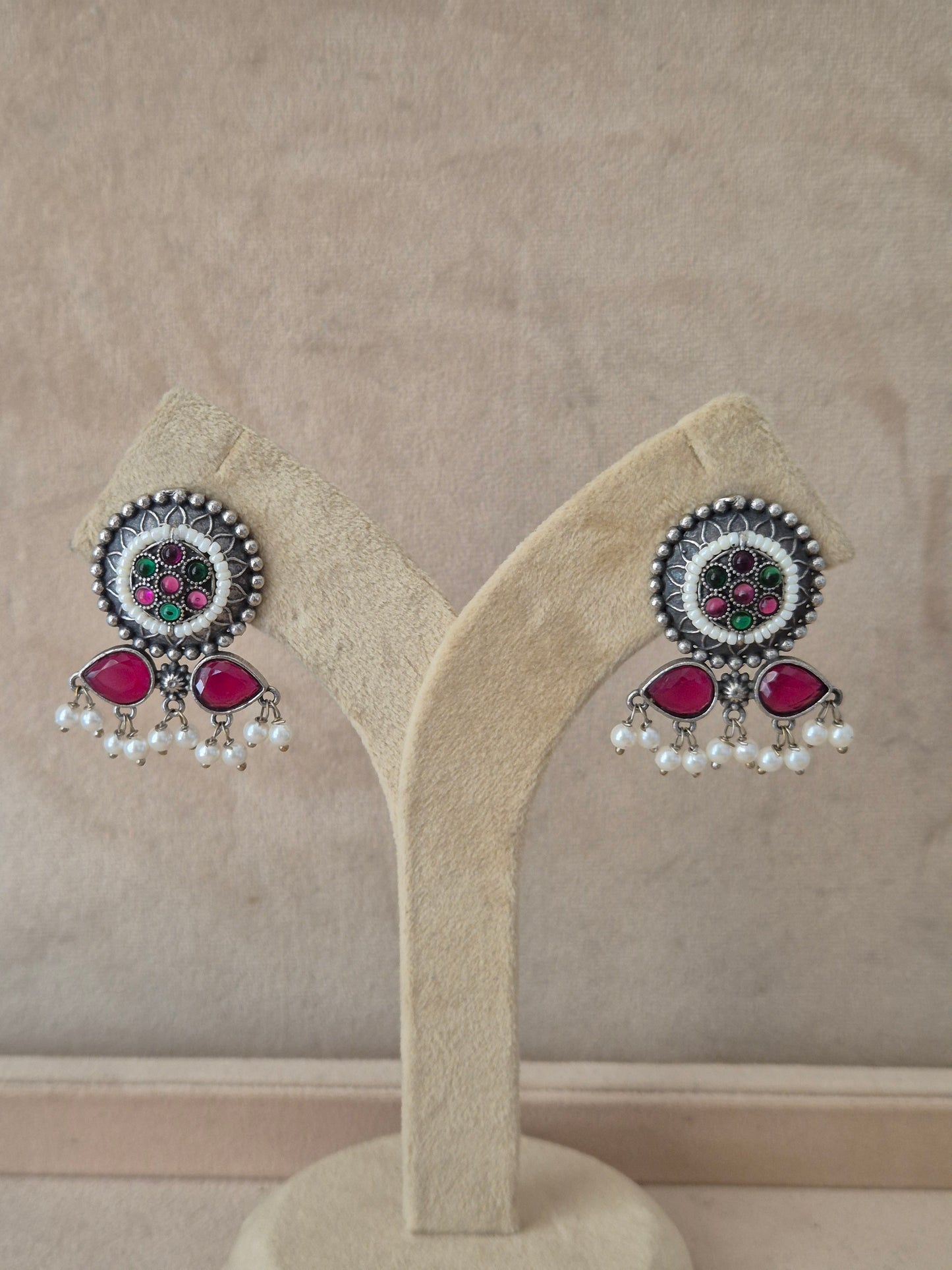 Modern Indian aesthetic silver-plated imitation jewelry earrings featuring a circular design, pink-green stones, and pearl beads  by naitri.in