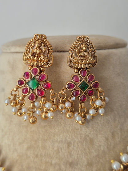 Artisanal Manisha earrings with white pearls, red and green stones, and mata laxmi on lotus flower by naitri.in