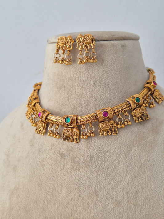 the golden Mannu Necklace Set elegantly draped over a textured jewelry display form. The close-up angle highlights the intricate metallic craftsmanship, fine beadwork, and contrasting stone embellishments by Naitri.in