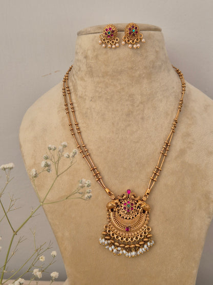 Handcrafted traditional gold-plated temple jewelry necklace featuring a delicate double-strand black and gold beaded chain, an intricate semicircular pendant with red and green stones, and dangling white pearl clusters with matching stud earring by naitri.in