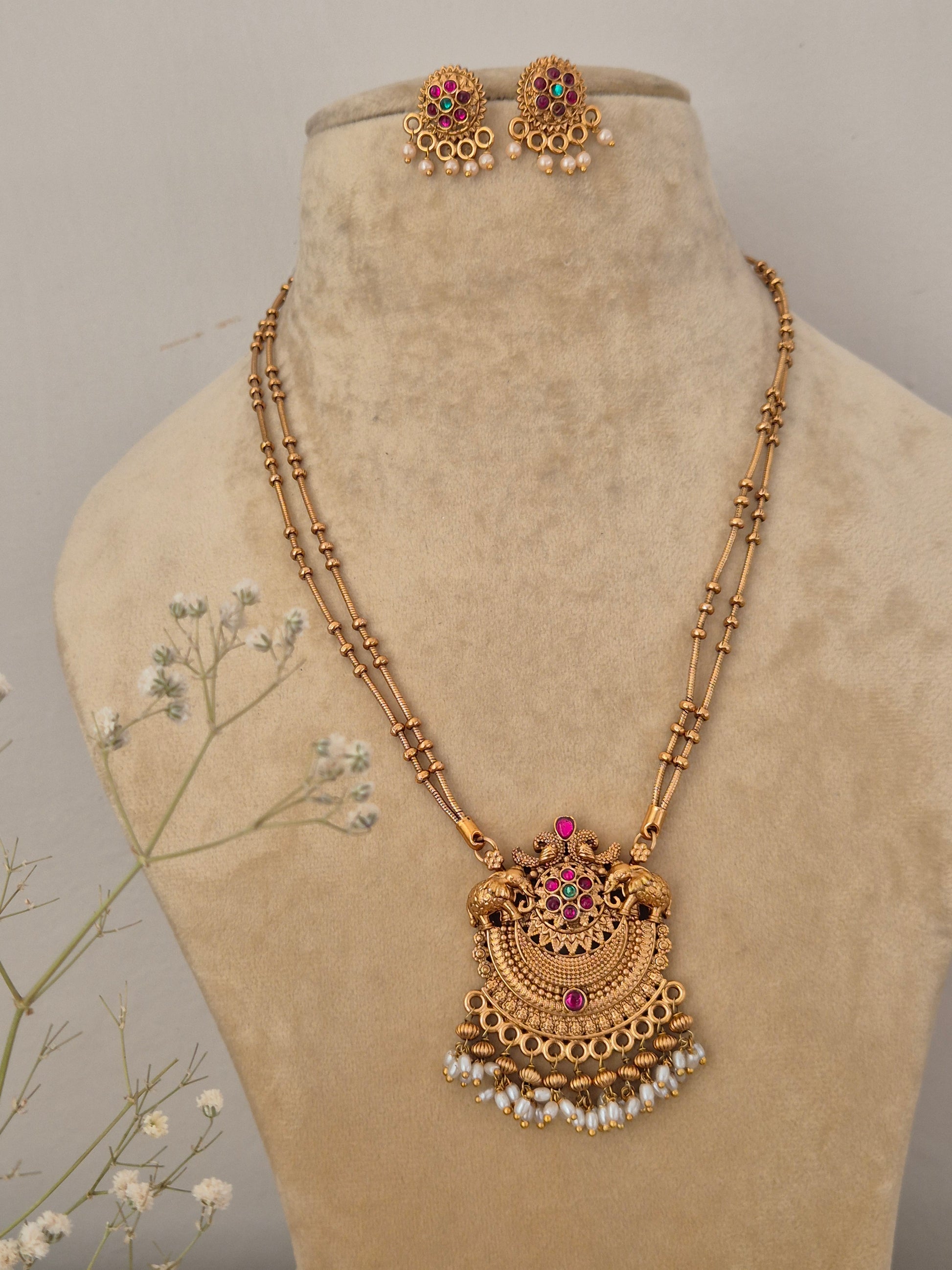 Handcrafted gold temple jewelry pendant necklace and matching earrings featuring colorful stones and white pearl cluster drops by naitri.in