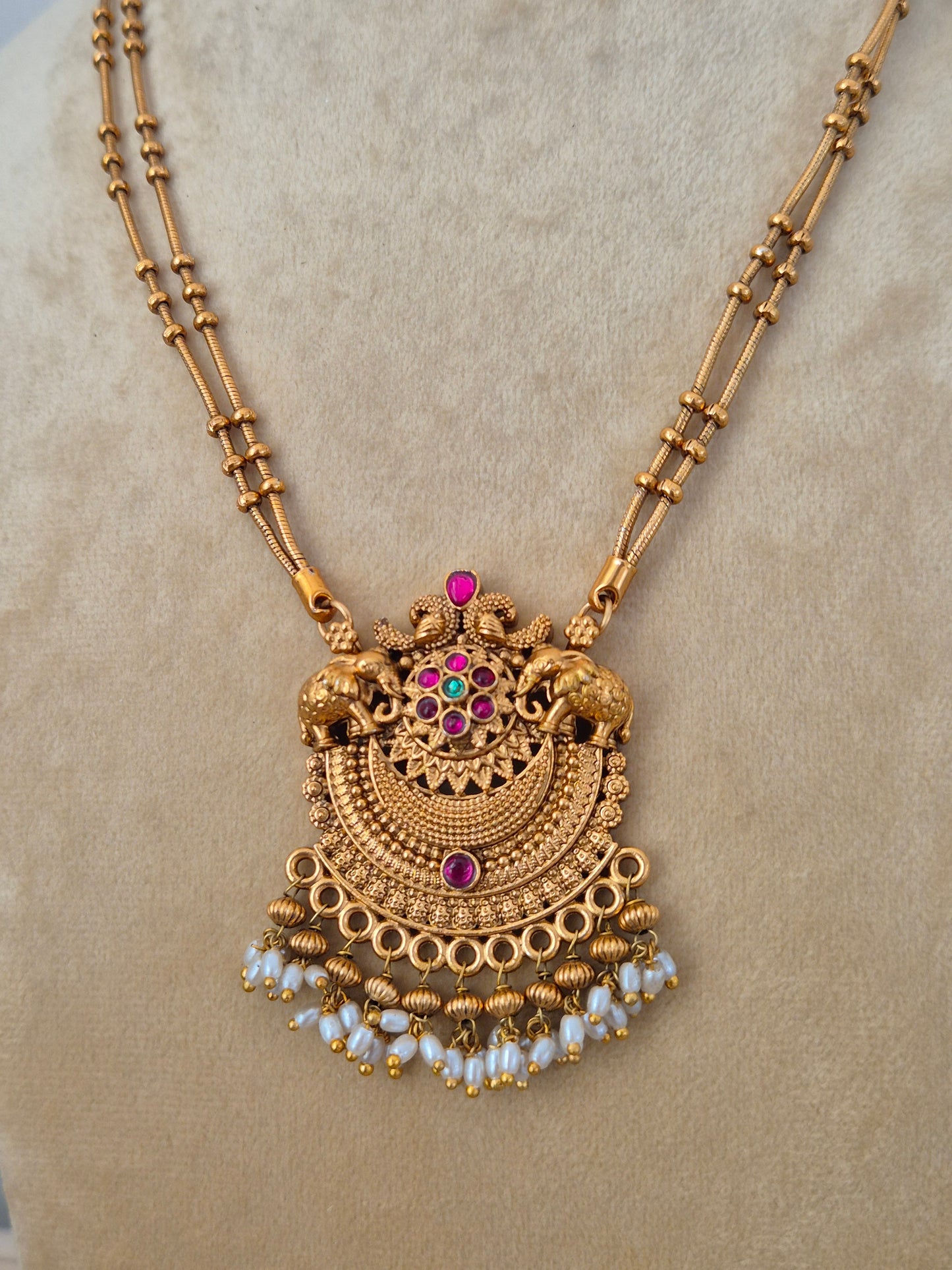 Traditional Indian antique-finish brass jewelry set showcasing a structured temple pendant with kemp stone embellishments, a dainty dual-layer black bead chain, and rich seed pearl fringes from the Naitri collection. by naitri.in