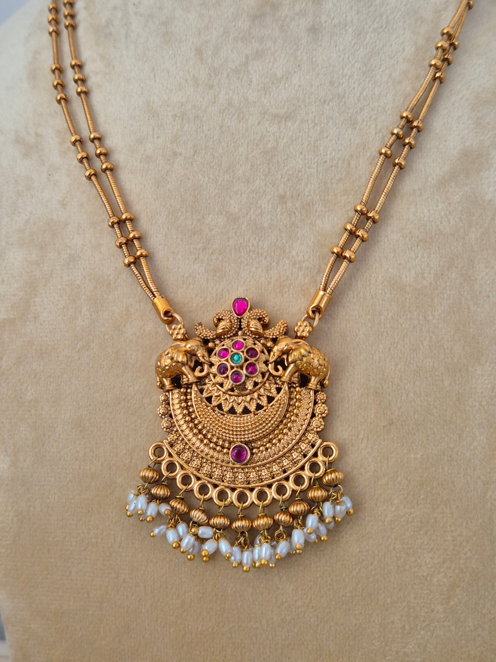 Traditional Indian antique-finish brass jewelry set showcasing a structured temple pendant with kemp stone embellishments, a dainty dual-layer black bead chain, and rich seed pearl fringes from the Naitri collection. by naitri.in