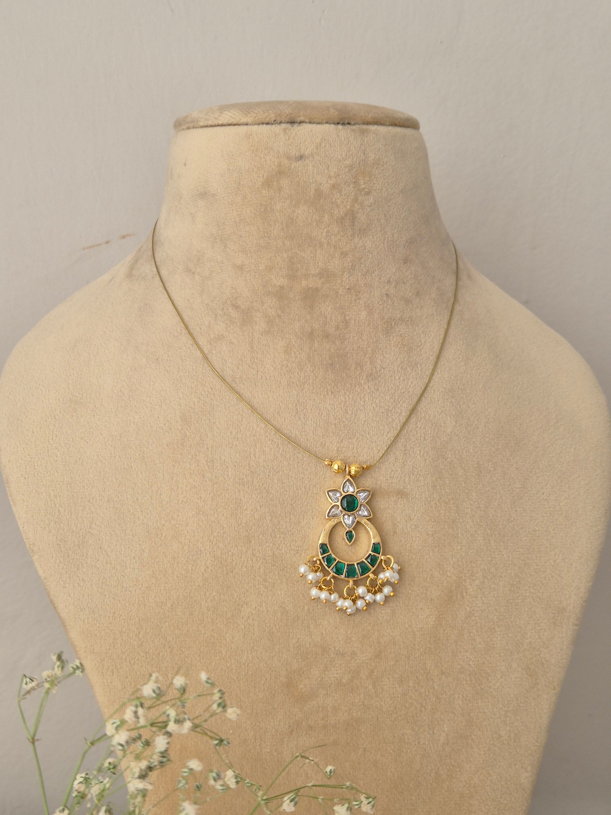Golden crescent moon pendant necklace with clear and green stonework and small pearl hangings by naitri.in