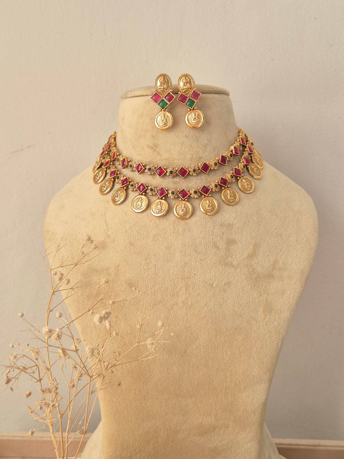 Mayra Necklace Set featuring traditional gold temple motifs with vibrant ruby and emerald stone accents and matching earrings by Naitri.in