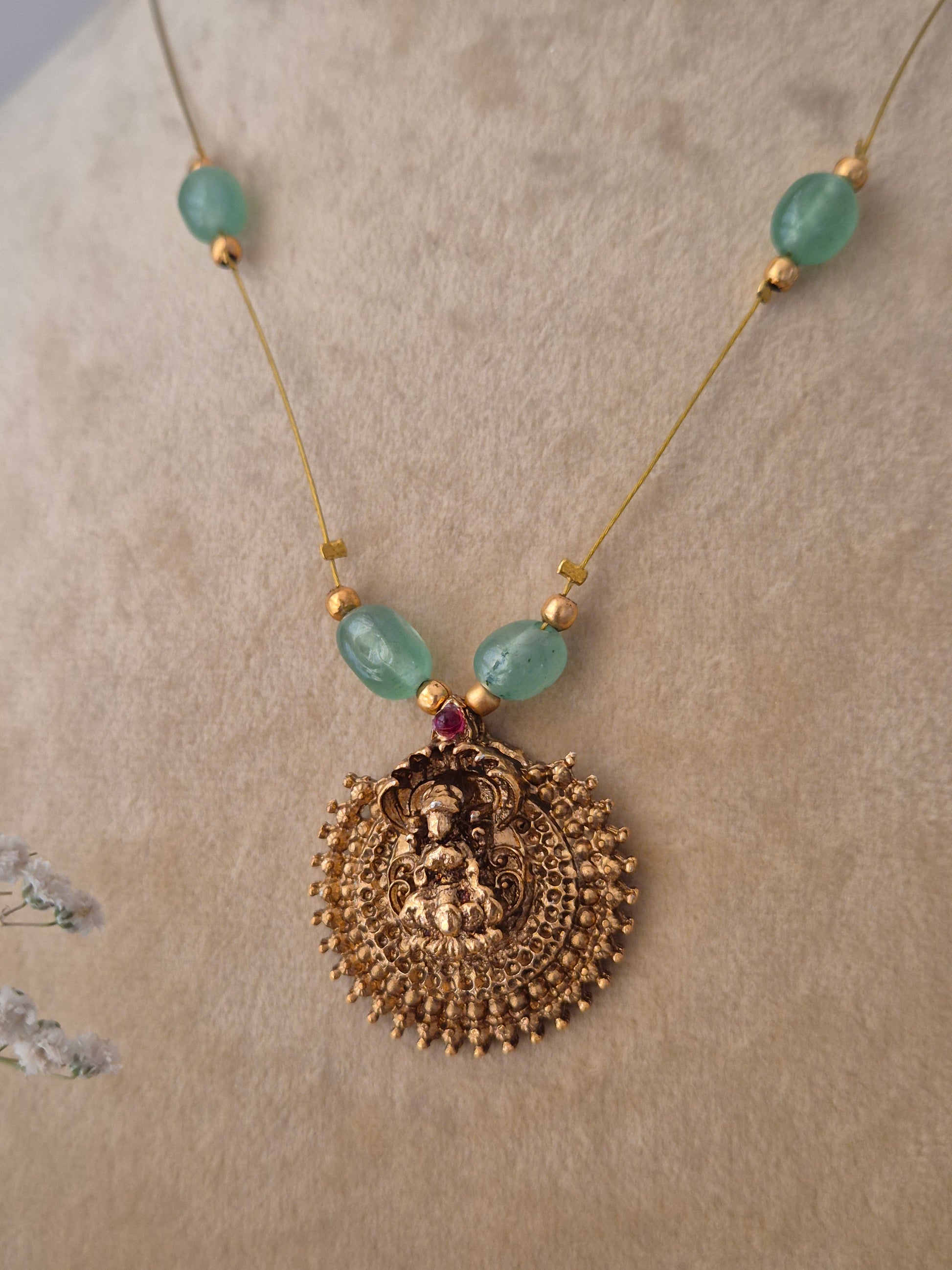 Handcrafted gold-polished necklace with five green gemstone beads and a large filigree pendant on a thin invisible chain, by naitri.in