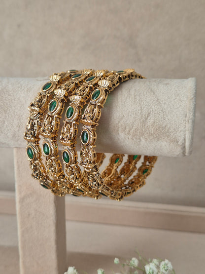 Traditional Indian gold-plated antique bangles adorned with oval green gemstone accents, Antique gold-plated bangle set decorated with green gemstones by naitri.in