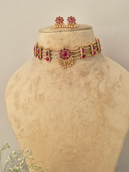 Gold-plated ethnic choker necklace featuring ruby-red gemstone accents and matching hanging stud earrings, by naitri.in