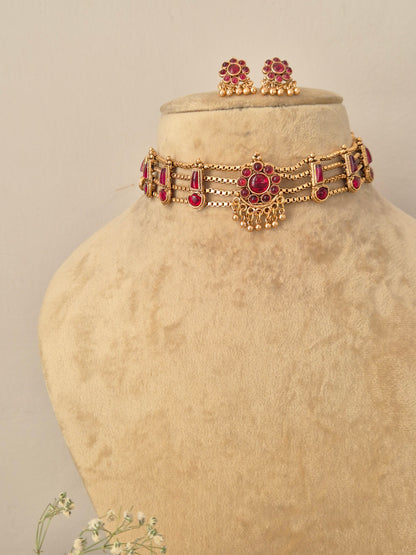 Handcrafted antique gold statement jewelry set decorated with intricate traditional patterns and red gemstone details, ideal for festive or wedding wear by naitri.in