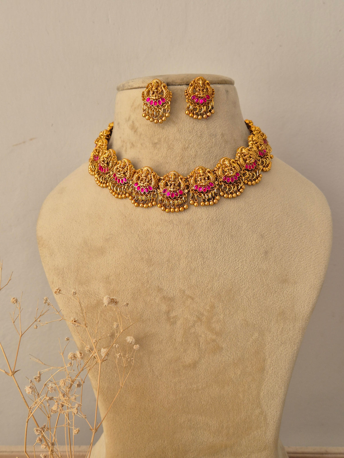 Meher Necklace Set featuring traditional gold temple motifs with vibrant ruby stone accents and matching earrings by Naitri.in