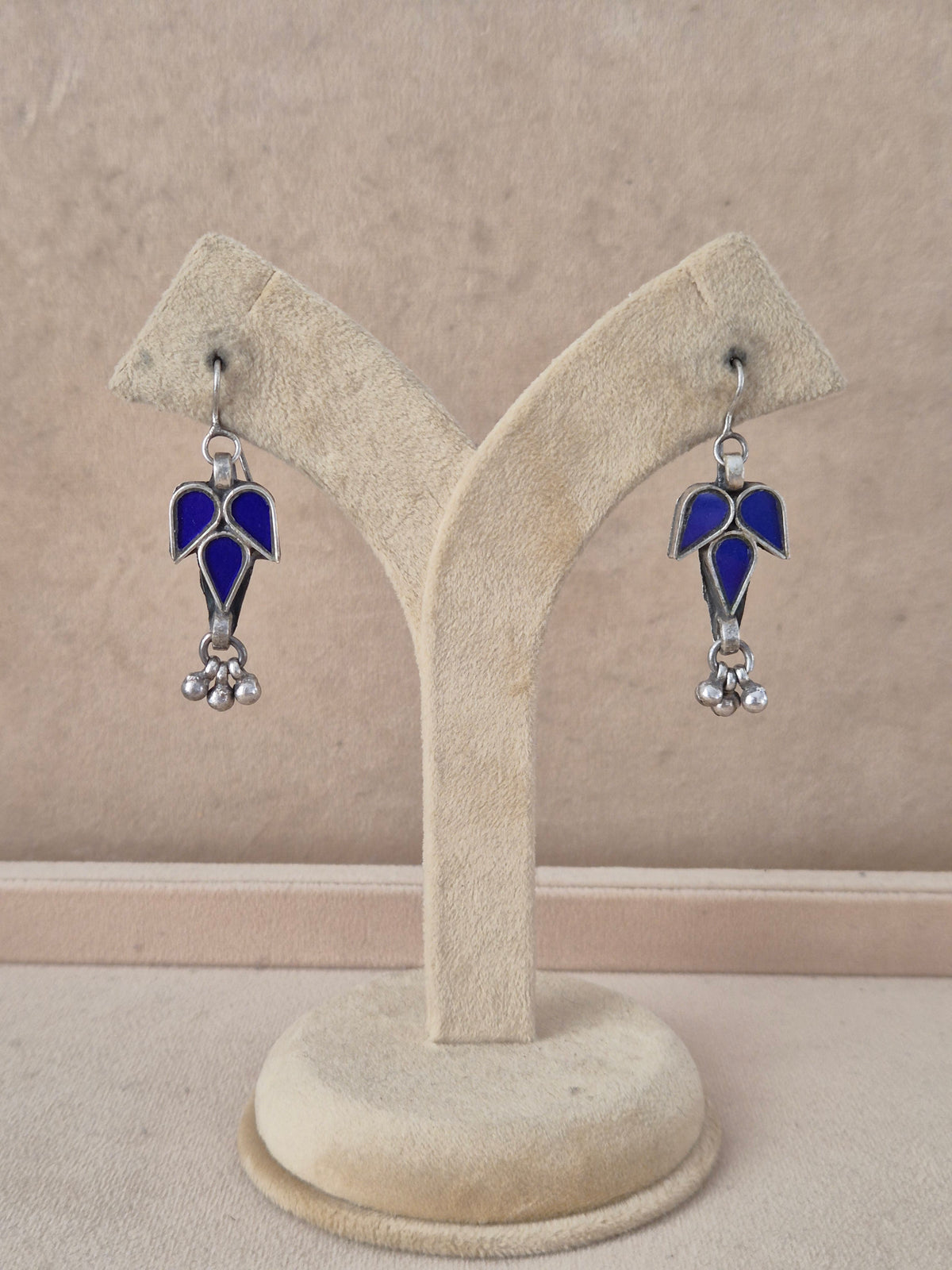 Pair of blue leaf-shaped glass drop earrings with silver bead detail. Mia royal blue glass dangle earrings with silver embellishments by naitri.in