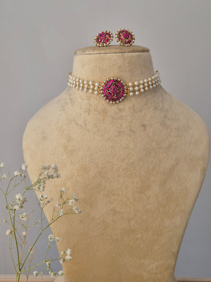 Choker Set featuring a multi-strand white pearl choker with a central pink stone floral pendant and matching pink stud earrings by naitri.in
