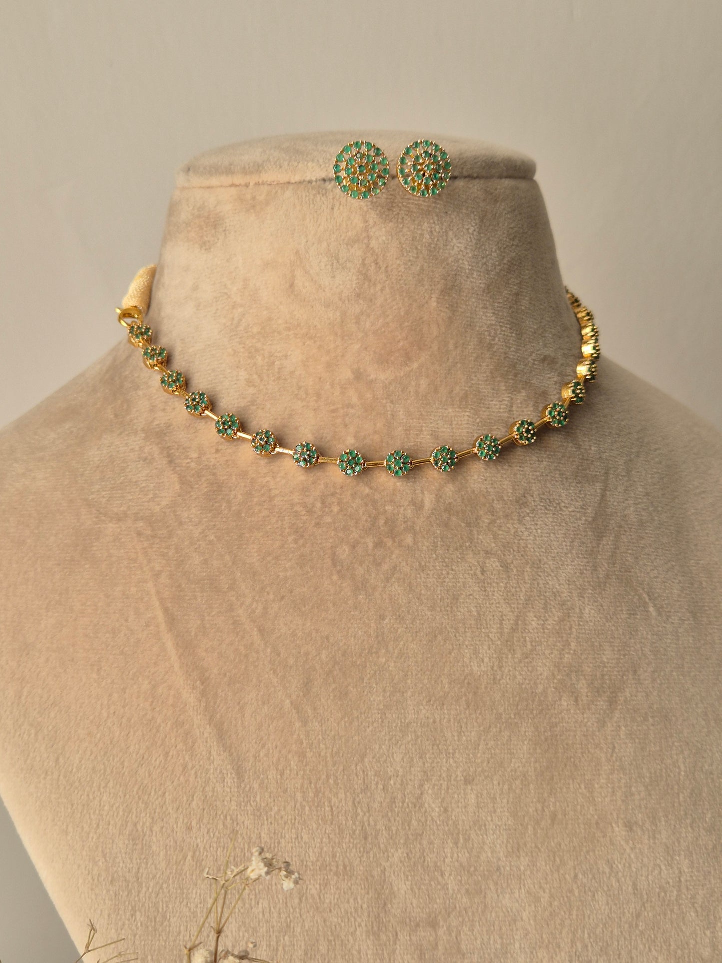 Minimalist Champa gold necklace and earring set with green stones and floral motifs by naitri.in