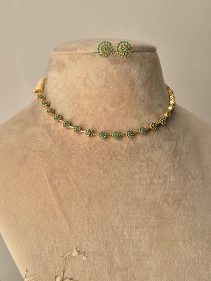 Minimalist Champa gold necklace and earring set with green stones and floral motifs by naitri.in
