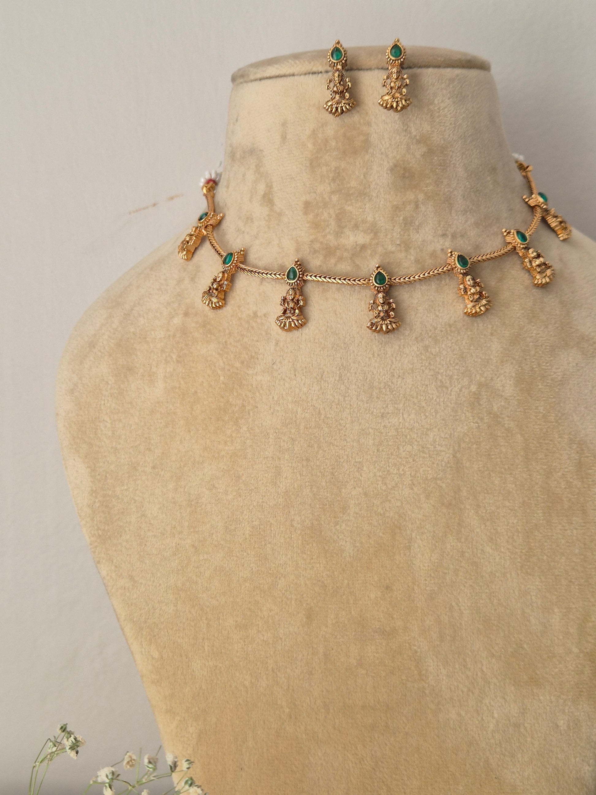 Handcrafted antique gold statement jewelry set showcasing intricate traditional motifs and green gemstone embellishments, ideal for festive styling by naitri.in