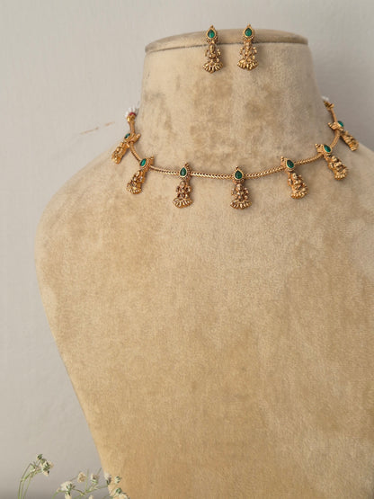 Handcrafted antique gold statement jewelry set showcasing intricate traditional motifs and green gemstone embellishments, ideal for festive styling by naitri.in