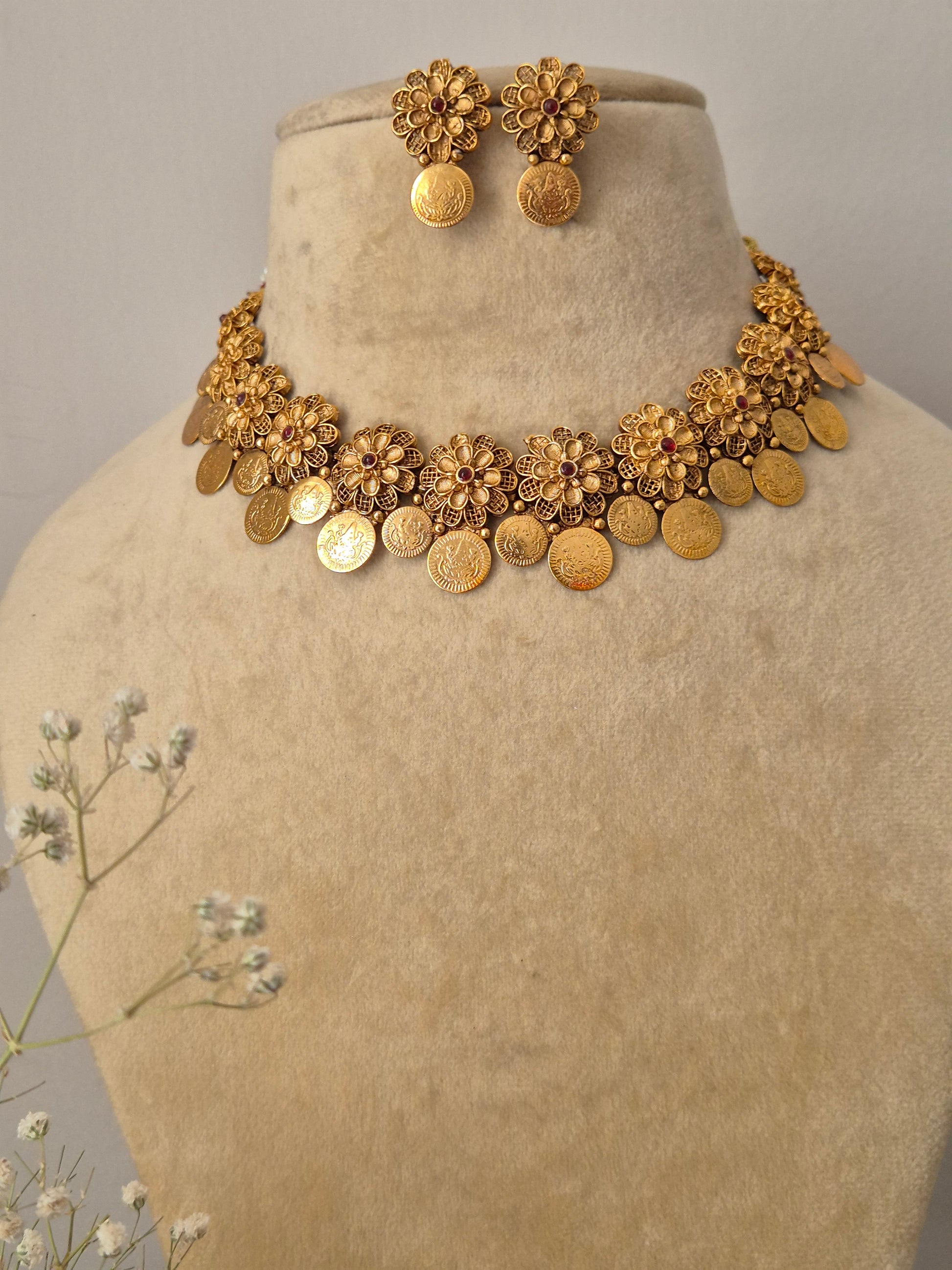 Handmade brass alloy necklace set with a polished golden finish, featuring classic floral stampings and a structured coin drop silhouette by naitri.in