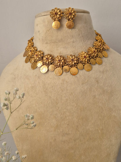 Handmade brass alloy necklace set with a polished golden finish, featuring classic floral stampings and a structured coin drop silhouette by naitri.in
