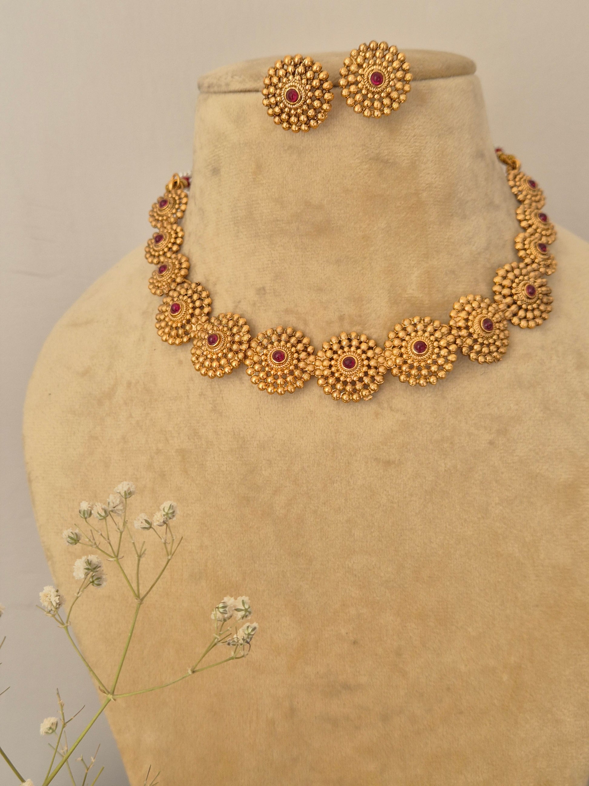 Monalisa Necklace Set: Gold-polished ethnic choker with floral motif red stone embellishments and coordinating stud earrings.