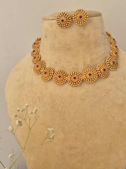 Monalisa Necklace Set: Gold-polished ethnic choker with floral motif red stone embellishments and coordinating stud earrings.