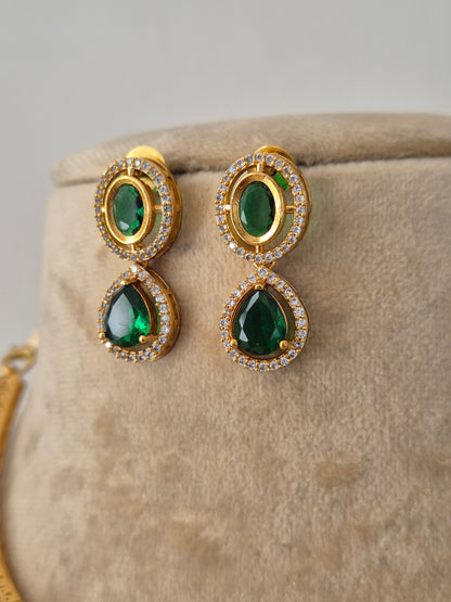 Gold-plated ethnic earrings featuring a prominent oval-cut green stone pendant surrounded by crystals teardrop earrings by naitri.in