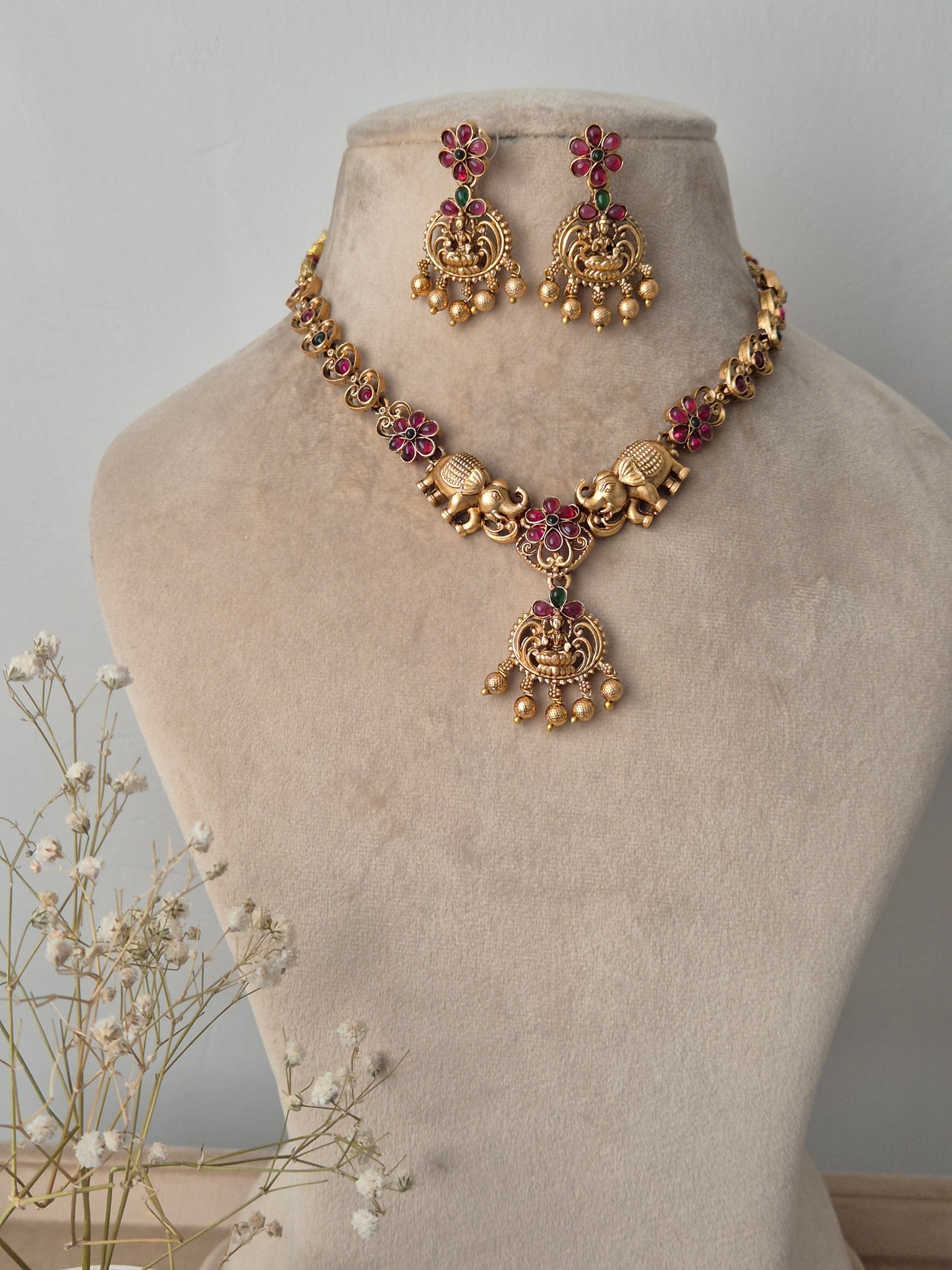 Gold necklace and earrings with red- green stones on the necklace