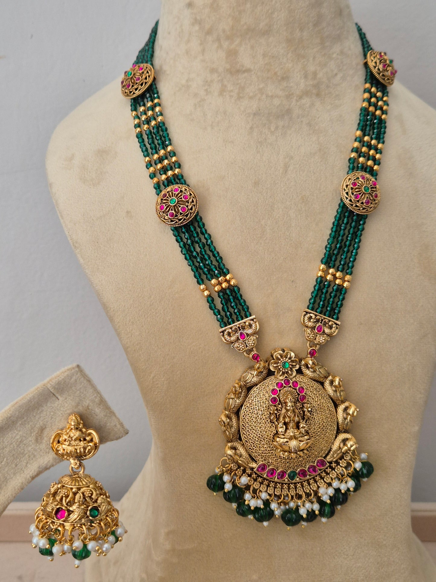 Ornate gold necklace with green beads and red gemstones, Gold-plated temple pendant necklace with green beaded strands and matching jhumka earrings by naitri.in