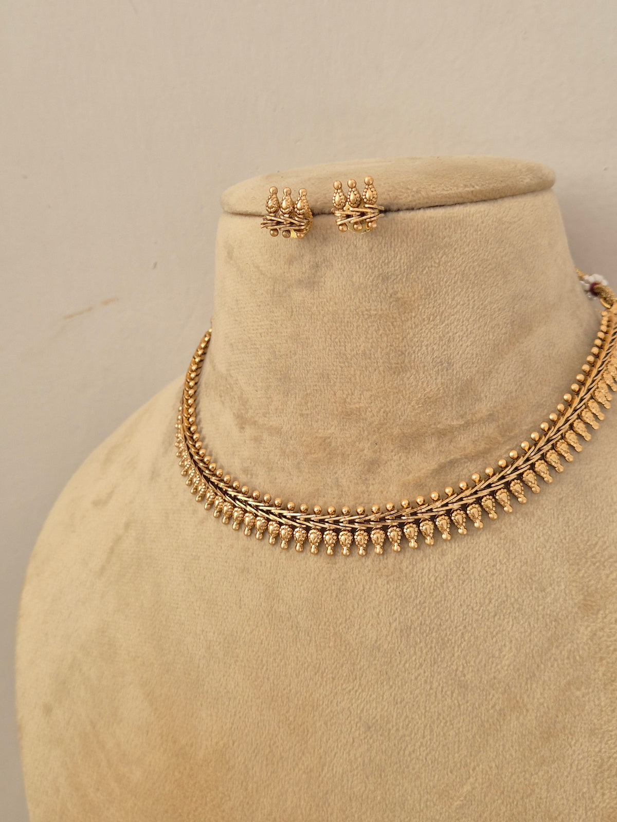 A gold-toned necklace and matching stud earrings by naitri.in