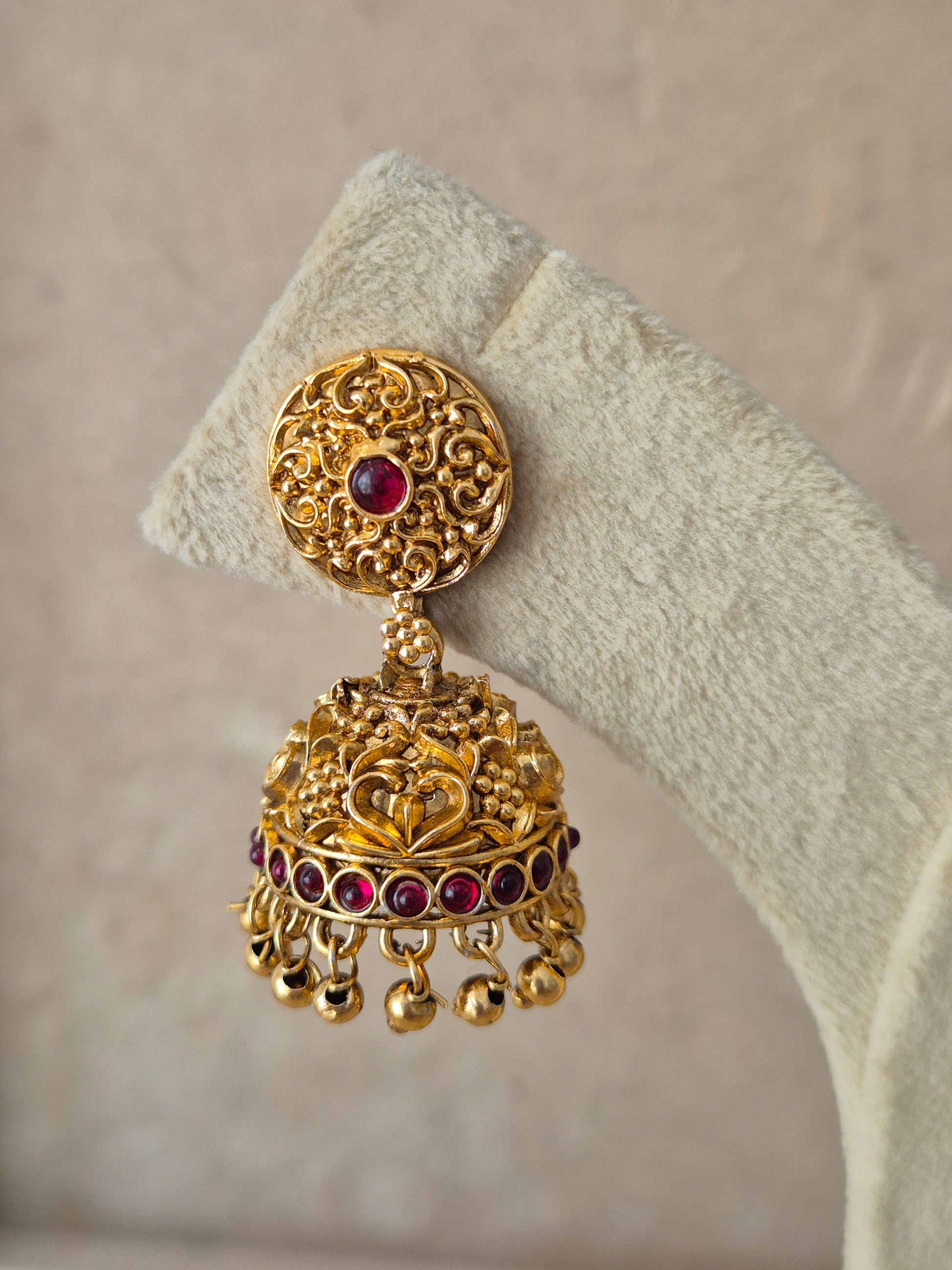 Handcrafted ethnic Indian gold-plated Jhumki earrings with red stones and hanging beads for bridal or festive wear.